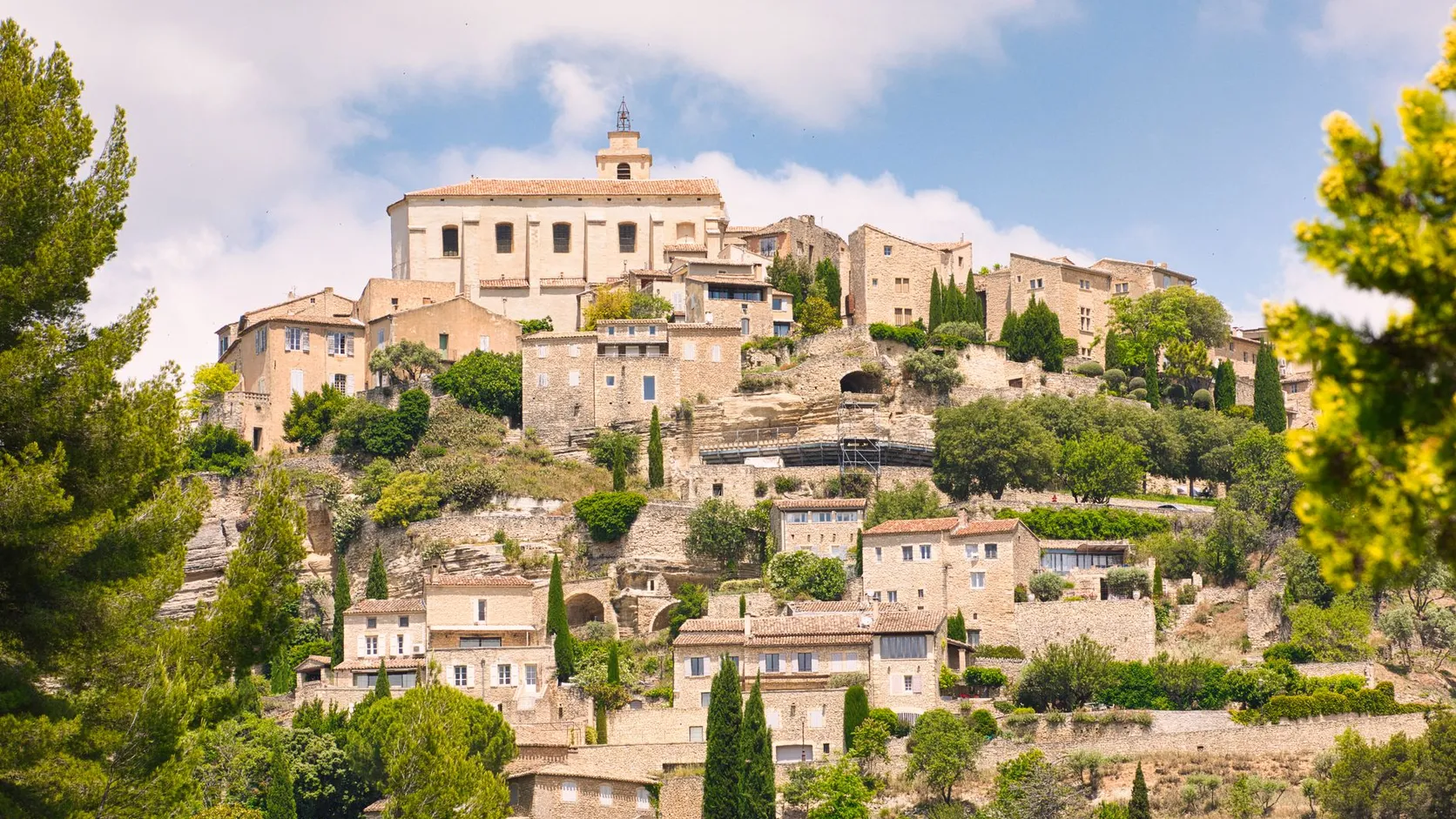 Village perché de Provence aux maisons de pierre étagées sur la colline, dominé par une église, entre cyprès et pins
